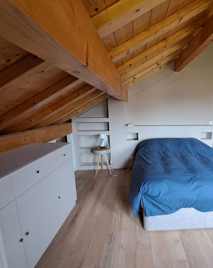 Photo charpente en bois dans une chambre avec un lit bleu